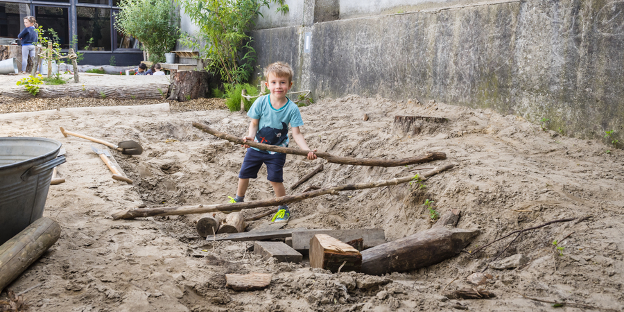 Een jongen bouwt een kamp met takken