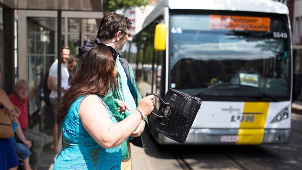 bus van De Lijn die aan een druk bevolkte halte komt aangereden