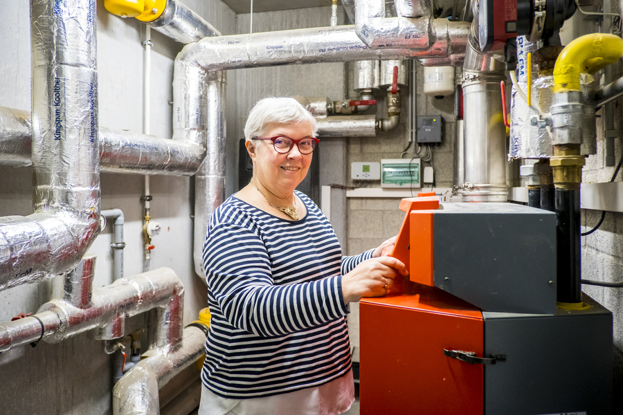 Vrouw toont de technische ruimte van het appartementsgebouw. We zien een moderne verwarmingsketel en geïsoleerde buizen. Vrouw toont de technische ruimte van het appartementsgebouw. We zien een moderne verwarmingsketel en geïsoleerde buizen.