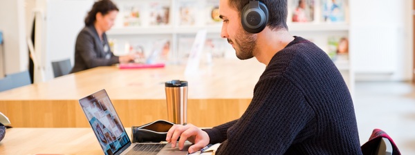 Man leest tijdschrift op eigen computer Man leest tijdschrift op eigen computer