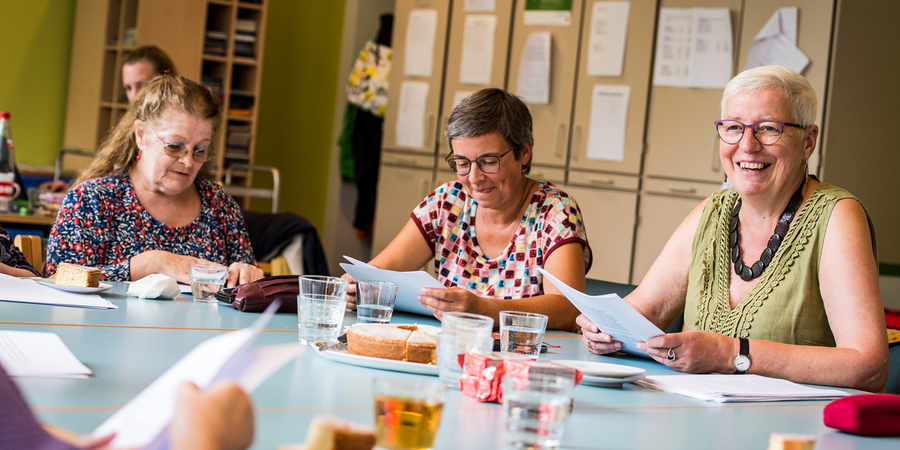 Drie 65-plussers gezellig samen aan tafel met cake en drankje Drie 65-plussers gezellig samen aan tafel met cake en drankje
