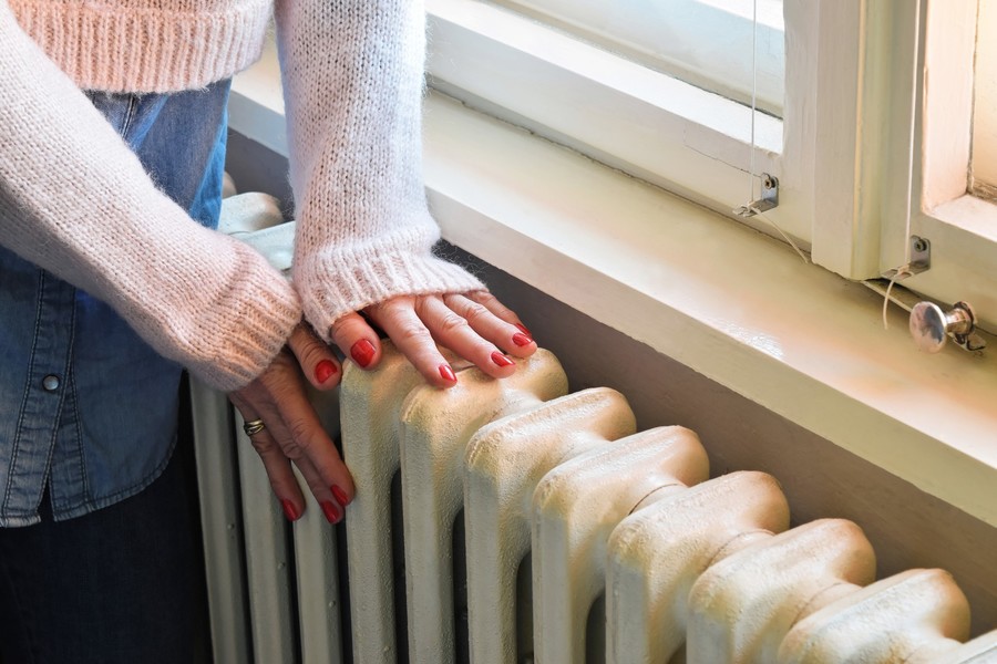 Vrouw voelt aan verwarming Vrouw voelt aan verwarming