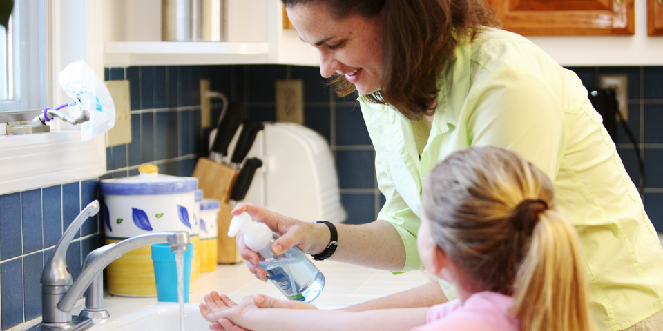 Een mama helpt de handen wassen van haar dochter