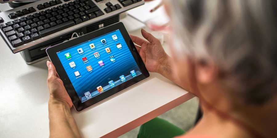 Een oudere dame werkt op een tabletcomputer.