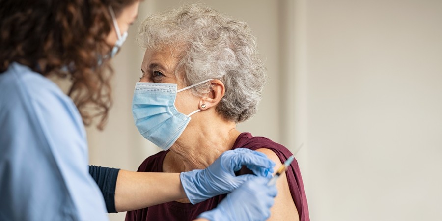 Oudere dame krijgt een vaccin in de arm Oudere dame krijgt een vaccin in de arm