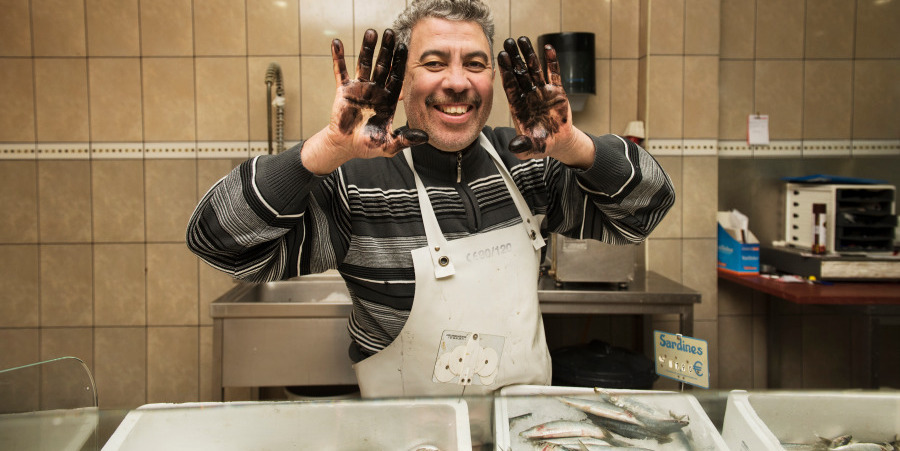 Een man in een viswinkel toont zijn handen, die zwart zien.