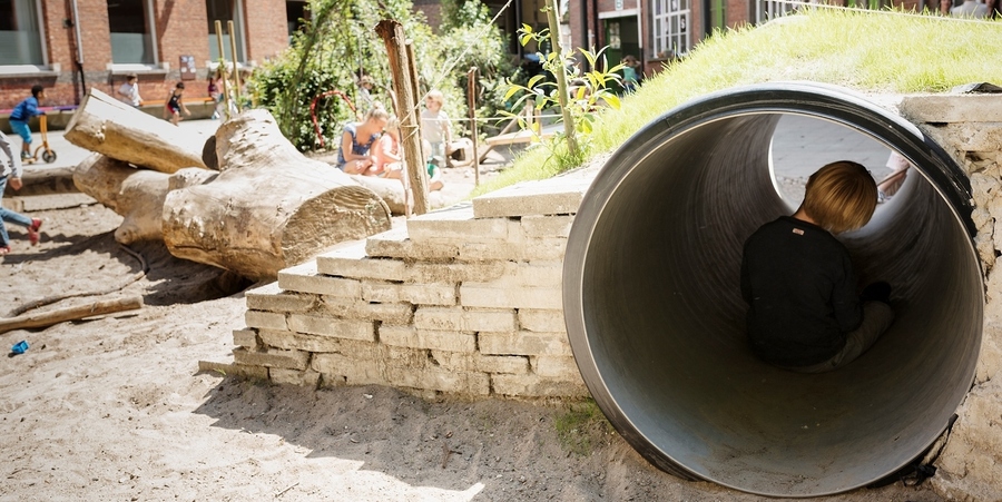 Speelplaats met heuvel en tunnel waar een kindje in zit Speelplaats met heuvel en tunnel waar een kindje in zit