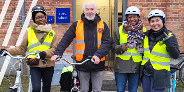 Vrijwilliger Luc gaat met drie deelneemsters van de fietsschool op de foto