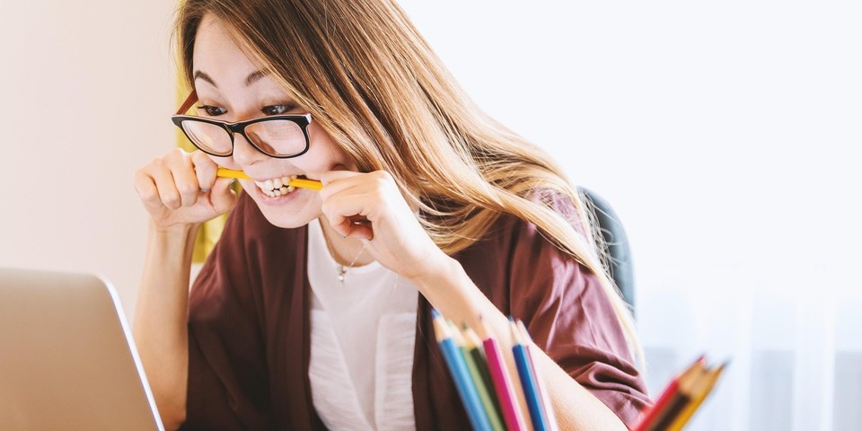 Studente bijt op een potlood terwijl ze haar laptop bekijkt.
