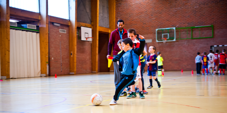 Kinderen op een voetbaltraining in een sporthal