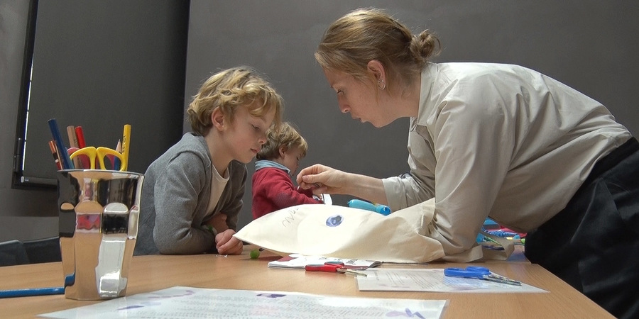 Een jongen krijgt uitleg van een begeleider in een workshop. Een jongen krijgt uitleg van een begeleider in een workshop.