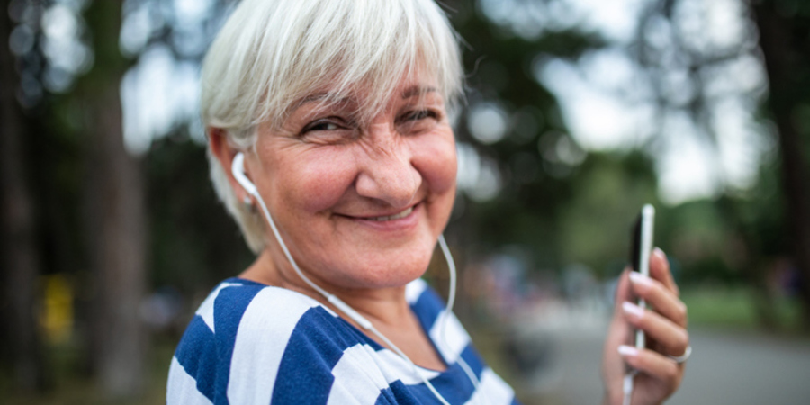 senior heeft oortjes in en luister via smartphone senior heeft oortjes in en luister via smartphone