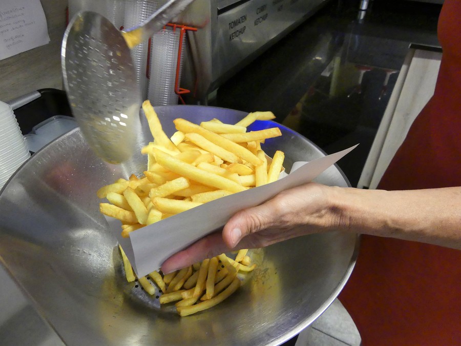 Marina schept een bakje frietjes in