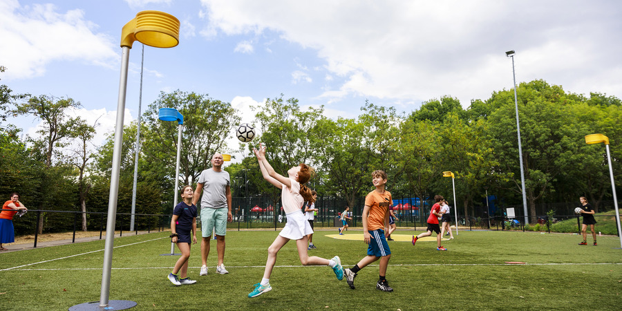 Meisje gooit de bal naar de korf tijdens een korfbal- en omnisportkamp op een zomers openluchtveld Meisje gooit de bal naar de korf tijdens een korfbal- en omnisportkamp op een zomers openluchtveld