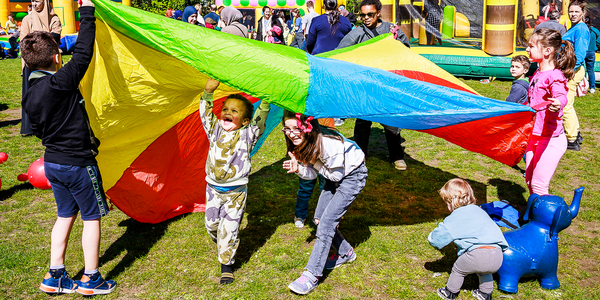 Spelende kinderen op gras onder een gekleurd zeil