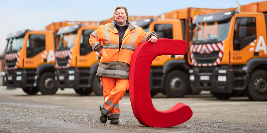 Chauffeur Brigitte poseert voor een aantal vrachtwagens van de stad