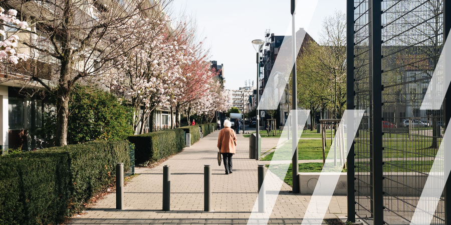 Een oudere vrouw wandelt op een trage weg tussen een appartementsgebouw en groen