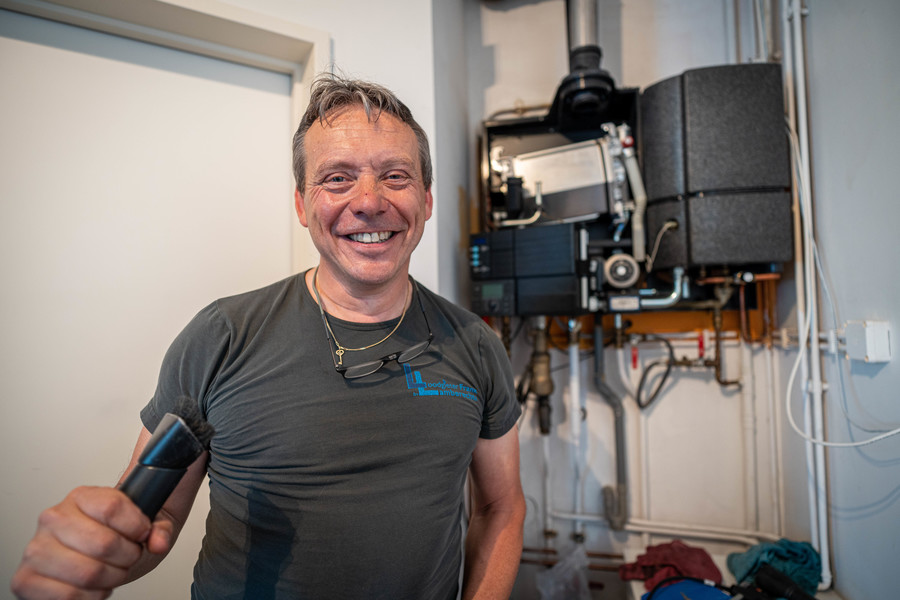 Frank Lamberechts lacht naar de camera terwijl hij een stofzuiger vastneemt