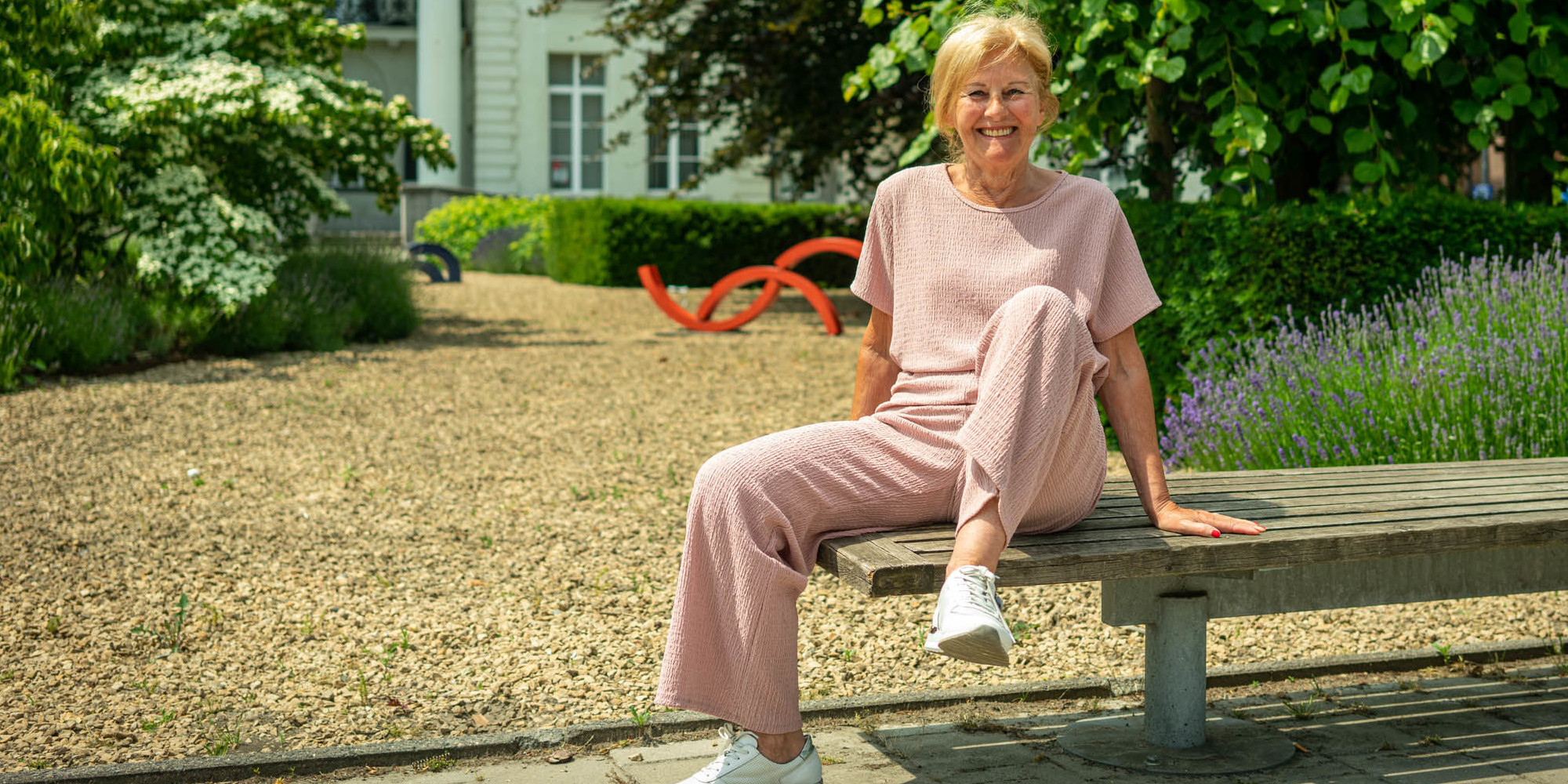 Oudere vrouw die een oefening toont aan één van de bezinningsbankjes Oudere vrouw die een oefening toont aan één van de bezinningsbankjes