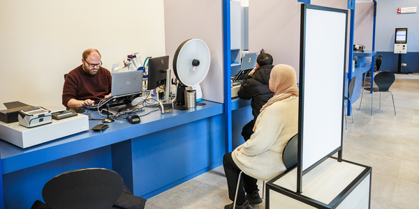 Vrouw laat pasfoto nemen aan het loket door de loketmedewerker.