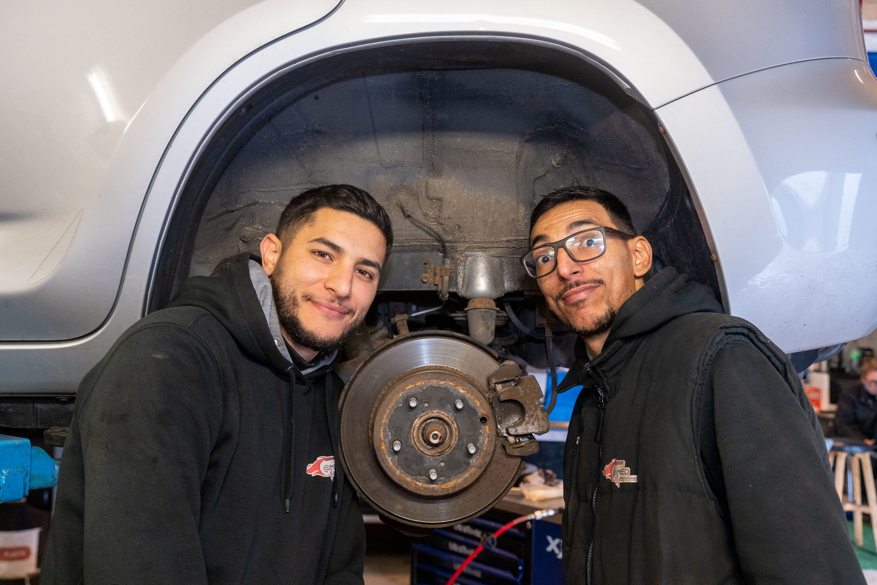 Het duo poseert met hun hoofden in een wielkuip, waarbij het wiel is weggehaald en de schijfrem zichtbaar is Het duo poseert met hun hoofden in een wielkuip, waarbij het wiel is weggehaald en de schijfrem zichtbaar is