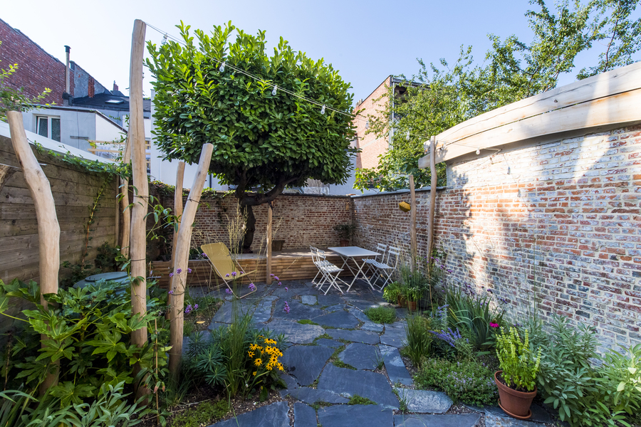 Zicht op tuin met op het einde een boom in houten platform Zicht op tuin met op het einde een boom in houten platform