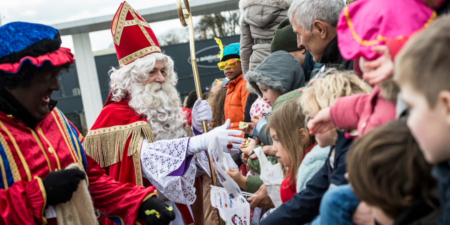 Sinterklaas en een zwarte piet schudden handen met en delen snoep uit aan kinderen. Sinterklaas en een zwarte piet schudden handen met en delen snoep uit aan kinderen.