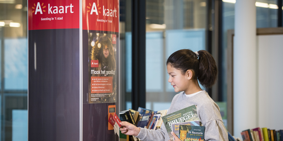 meisje spaart A-kaartpunt aan zuil in bibliotheek meisje spaart A-kaartpunt aan zuil in bibliotheek