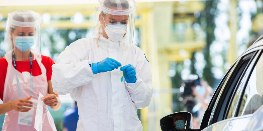 Twee vrouwen met mondmasker en andere bescherming nemen naast een wagen een coronatest af in het testdorp TestCovid. Twee vrouwen met mondmasker en andere bescherming nemen naast een wagen een coronatest af in het testdorp TestCovid.