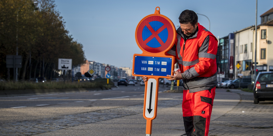 Stadsmedewerker zet digitaal parkeerverbdosbord op straat