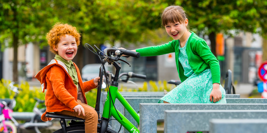 2 kinderen op een fiets geparkeerd aan een fietsbeugel 2 kinderen op een fiets geparkeerd aan een fietsbeugel