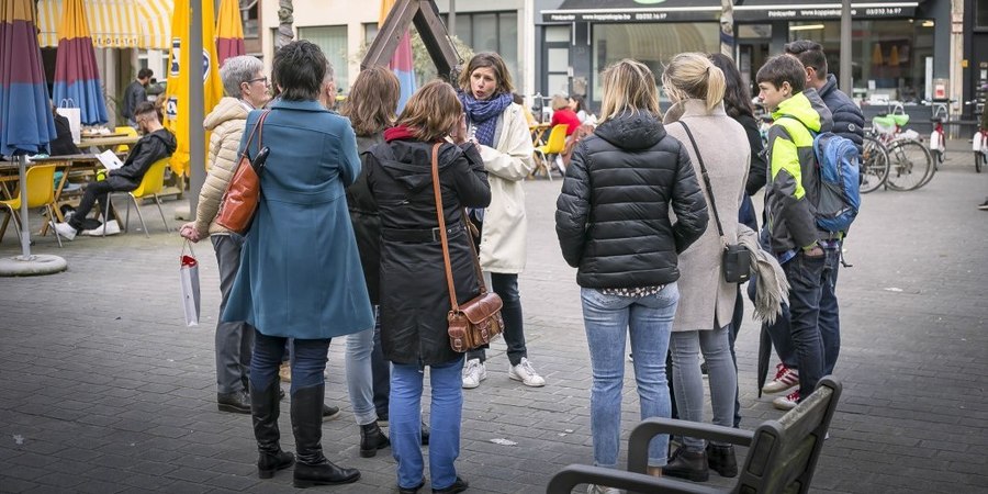 Gids Katrien van Geystelen met een groep luisteraars rond haar Gids Katrien van Geystelen met een groep luisteraars rond haar
