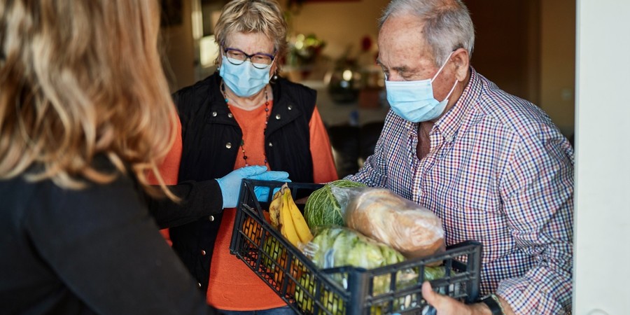 Vrouw brengt boodschappen aan huis bij een koppel Vrouw brengt boodschappen aan huis bij een koppel