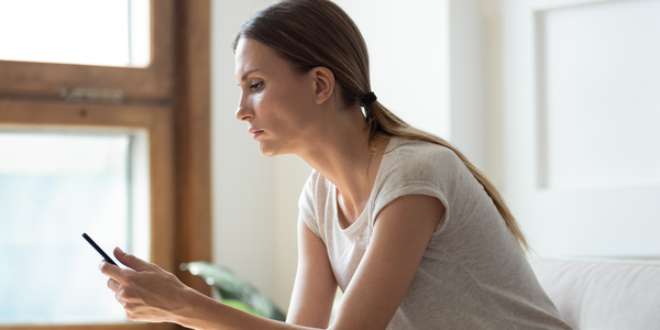 Een vrouw zit neer en typt op haar smartphone.