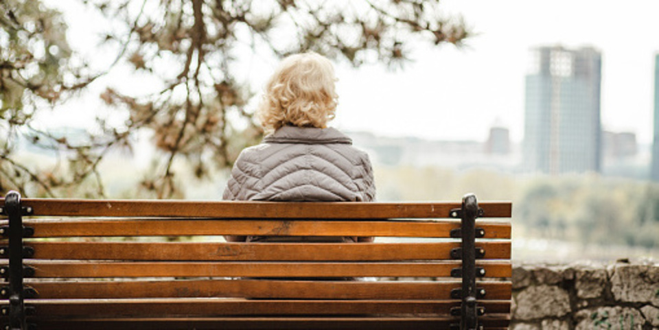 Een vrouw zit op een bank met haar rug naar de camera.