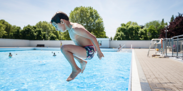 Een jongetje springt in het groot bad van zwembad De Molen op Linkeroever