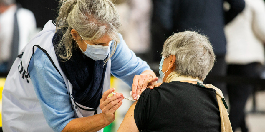 Mevrouw krijgt vaccin in bovenarm. Mevrouw krijgt vaccin in bovenarm.