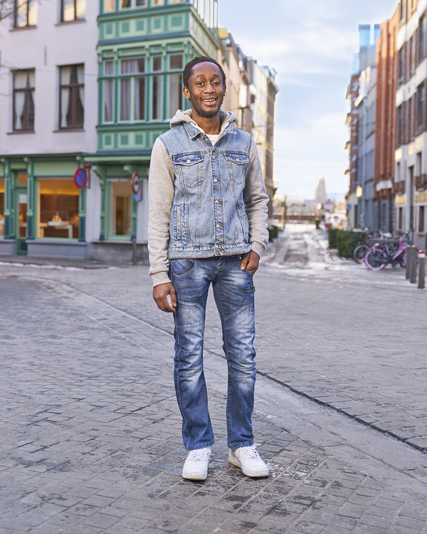 Emmanuel poseert lachend op straat voor de camera