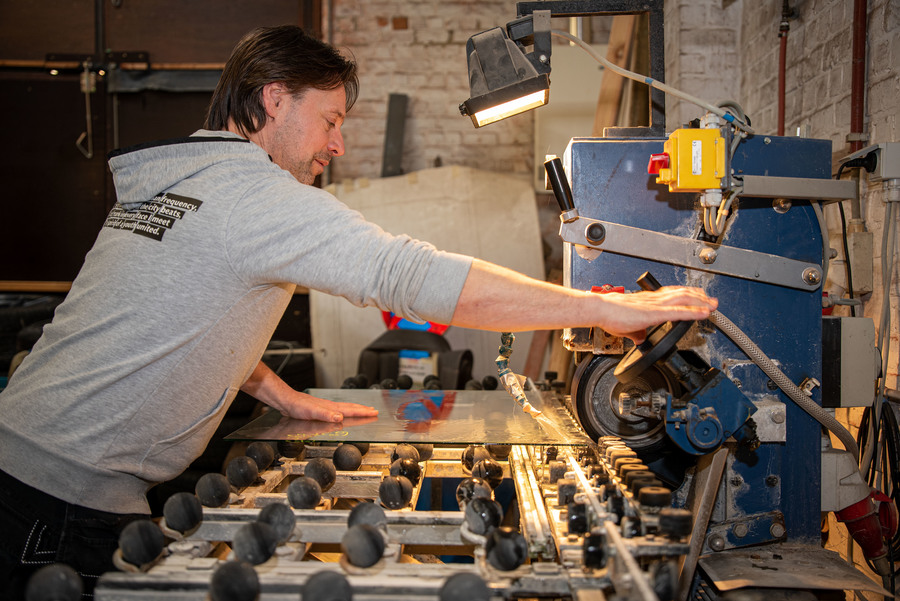 Man bedient een machine die glas snijdt Man bedient een machine die glas snijdt