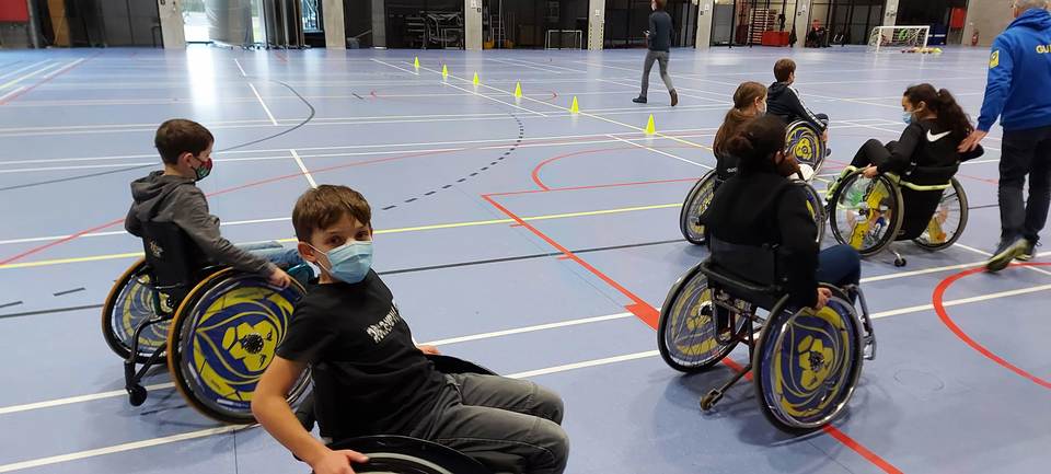 Het Junior Team leert omgaan met een rolstoel tijdens een initiatie door Merksem Handbal.