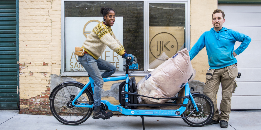 Vrouw en man op bakfiets vervoeren tuinafval Vrouw en man op bakfiets vervoeren tuinafval
