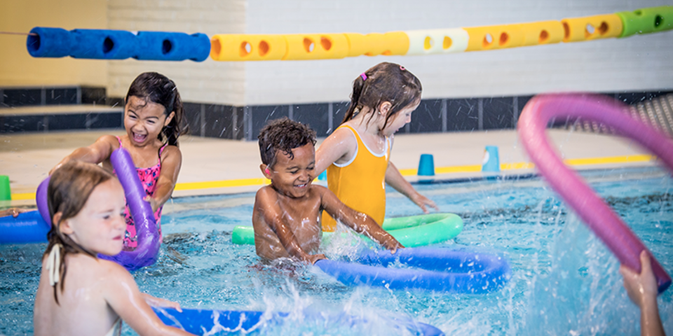 4 kindjes die plezier maken in het zwembad tijdens een Antwerpse Sportweek