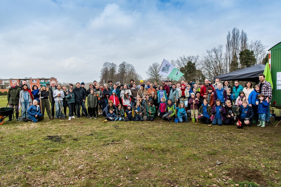 Vrijwilligers die voedselbos Boskruit aanplanten poseren voor een groepsfoto.