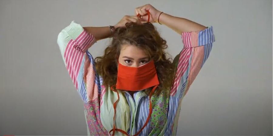 Een mevrouw doet een mondmasker rond haar gezicht. Een mevrouw doet een mondmasker rond haar gezicht.