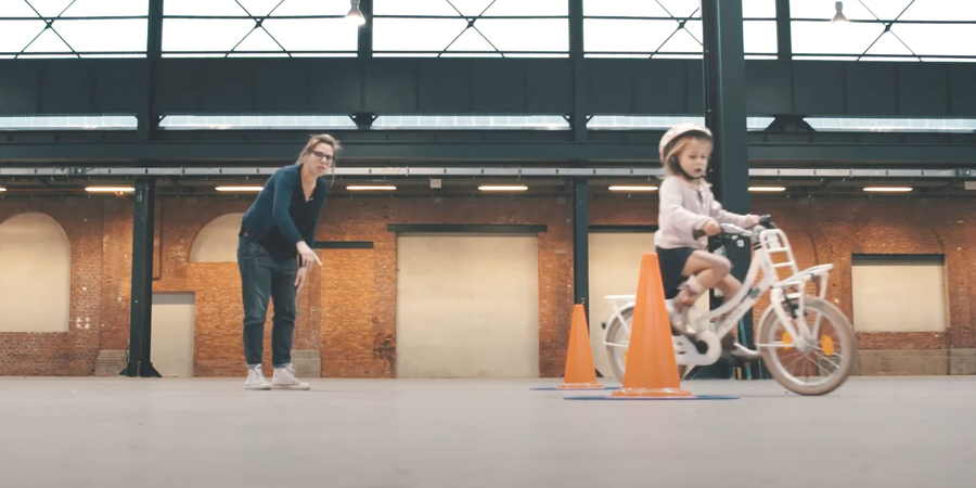 Meisje dat op de fiets aan het slalommen in tussen oranje kegeltjes
