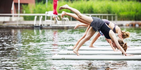 Dames die yoga doen op het kalme water van zwemvijver Boekenberg