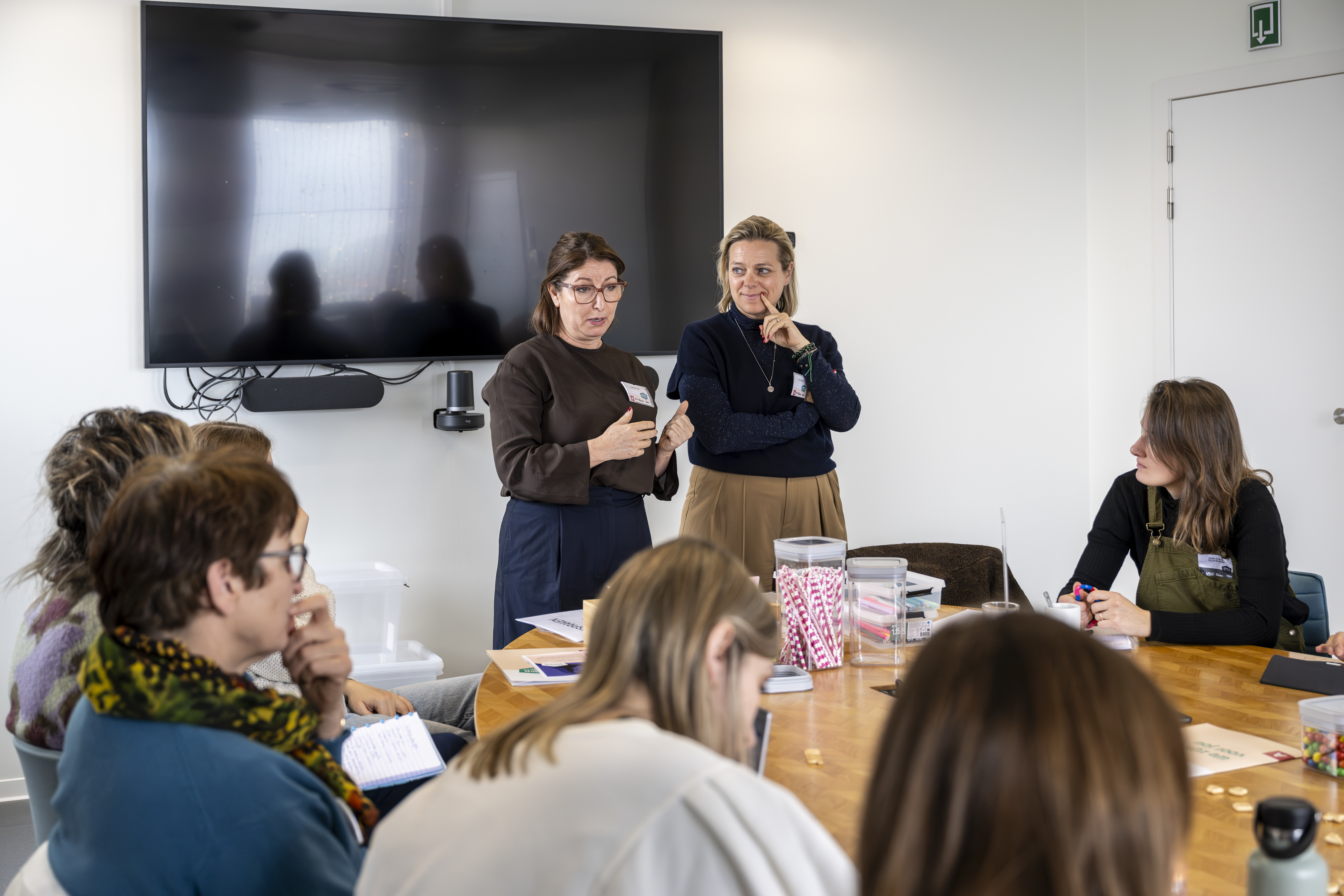 Twee personen spreken vooraan vergaderzaal
