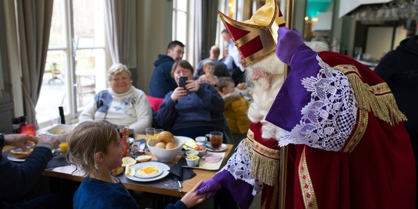 Sint geeft hand aan kind