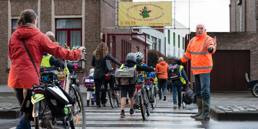 Ouders en leerlingen steken het zebrapad over voor de school Ouders en leerlingen steken het zebrapad over voor de school