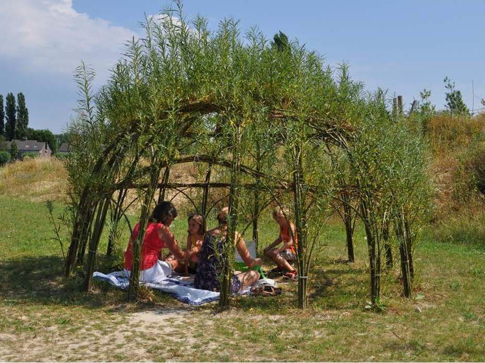 Een gezin picknickt in een wilgenhut